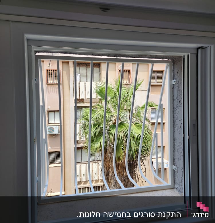 חלון עם סורגים לבנים ומסגרת לבנה